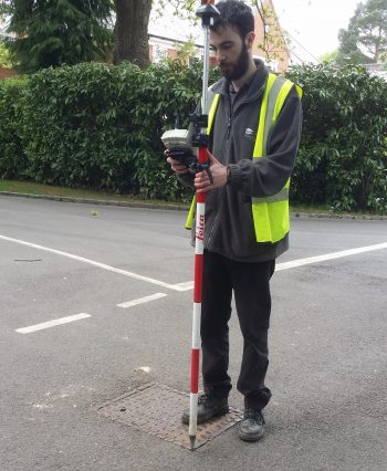 man standing on road using equipment for a topographic survey